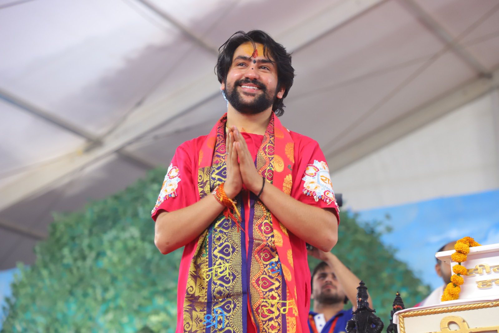 प्रणाम की मुद्रा में हाथ जोड़े मुस्कुराते हुए गुरुजी, श्री धीरेंद्र कृष्ण शास्त्री